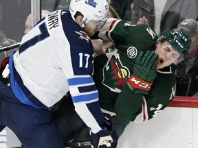 Winnipeg Jets' Adam Lowry (17) checks Minnesota Wild's Joel Eriksson Ek (14 during the third period in St. Paul, Minn., on Friday night.  (AP Photo/Hannah Foslien)MNHF115