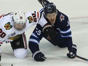 Winnipeg Jets centre Mark Scheifele (right) and Chicago Blackhawks forward Brandon Saad fall while battling for a loose puck in Winnipeg on Thursday. (Kevin King/Winnipeg Sun)