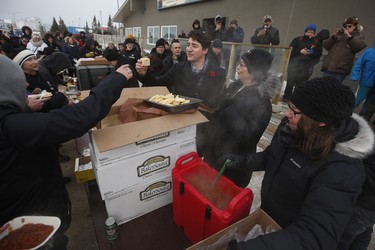 Prime Minister Justin Trudeau enjoys some bannock at a street party after announcing to the residents the opening of the repaired railway in Churchill, Manitoba Thursday, November 1, 2018. Prime Minister Justin Trudeau visited Churchill today to announce the opening of the railway and the Port of Churchill. THE CANADIAN PRESS/John Woods