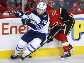 Winnipeg Jets' Jack Roslovic, left, checks Calgary Flames' Garnet Hathaway during first period NHL hockey action in Calgary, Wednesday, Nov. 21, 2018.THE CANADIAN PRESS/Jeff McIntosh