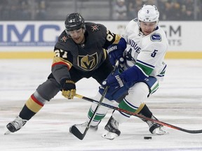 Golden Knights left wing Max Pacioretty (67) and Canucks defenceman Derrick Pouliot (5) vie for the puck during NHL action in Las Vegas on Oct. 24, 2018.