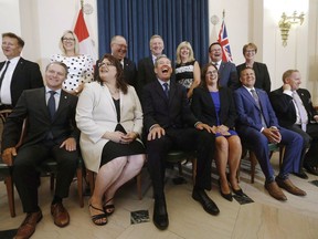 Manitoba's Progressive Conservative government will lay out its agenda for the coming year in the annual speech from the throne at the legislature this afternoon. Premier Brian Pallister, centre, and his ministers laugh during a team photo after he announced a cabinet shuffle at the Manitoba Legislature in Winnipeg on Wednesday, Aug. 1, 2018.