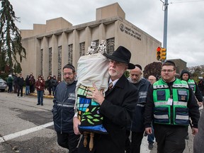 In this Oct. 29, 2018, file photo, Rabbi Jeffrey Myers, centre, of Tree of Life synagogue, carries their Torah to be stored elsewhere in Pittsburgh.