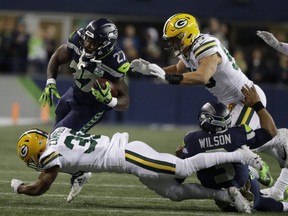 Seahawks running back Mike Davis (27) rushes past Packers defensive back Ibraheim Campbell (39) after getting some blocking from quarterback Russell Wilson (3) during NFL action in Seattle, Thursday, Nov. 15, 2018.