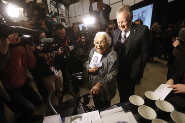 Clutching some $10 banknotes Wanda Robson, Viola Desmond's sister, spends the first $10 banknote at a launch of Canada's new $10 banknote, which has a portrait of Desmond, the first Canadian woman on a banknote, at the Canadian Museum For Human Rights in Winnipeg, Monday, Nov. 19, 2018. Bank of Canada Governor Stephen Poloz and Robson, officially launched the unique, vertically oriented purple bill. THE CANADIAN PRESS/John Woods