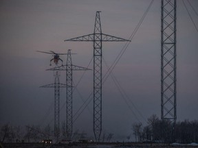 A helicopter lowers a transmission tower assembly in section S1 of Bipole III during construction of the line.