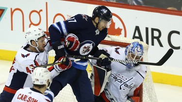 Winnipeg Jets centre Adam Lowry gets in the grill of  Washington Capitals goaltender Pheonix Copley as he is checked by forward Tom Wilson in Winnipeg on Wed., Nov. 14, 2018. Kevin King/Winnipeg Sun/Postmedia Network