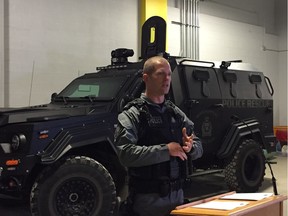 Const. Tyler Loewen of the Winnipeg Police Service Tactical Support Team addresses the media at police headquarters on Friday, with the Armoured Rescue Vehicle (ARV1) in the background. ARV1 and a marked police cruiser were hit by bullets during a 12-hour armed standoff in the 300 block of Bannerman Avenue on Wednesday, Nov. 7.