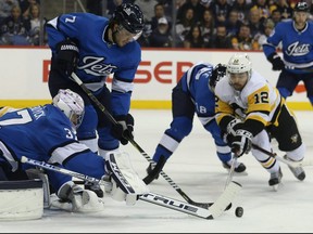 Winnipeg Jets goaltender Connor Hellebuyck pushes the puck as Pittsburgh Penguins forward Dominik Simon dives in Winnipeg on Tues., Nov. 27, 2018. Kevin King/Winnipeg Sun/Postmedia Network