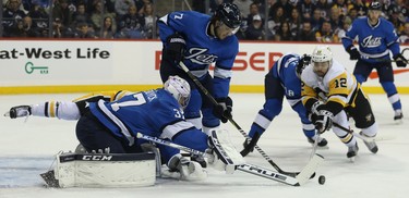 Winnipeg Jets goaltender Connor Hellebuyck pushes the puck as Pittsburgh Penguins forward Dominik Simon dives in Winnipeg on Tues., Nov. 27, 2018. Kevin King/Winnipeg Sun/Postmedia Network