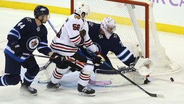 Winnipeg Jets goaltender Connor Hellebuyck steers aside a shot from Chicago Blackhawks defenceman Erik Gustaffson, who is defended by Josh Morrissey, in Winnipeg on Thurs., Nov. 29, 2018. Kevin King/Winnipeg Sun/Postmedia Network