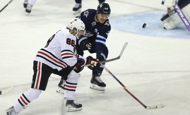 Chicago Blackhawks forward Patrick Kane (left) throws a backhand at the net as he's defended by Winnipeg Jets centre Mark Scheifele in Winnipeg on Thurs., Nov. 29, 2018. Kevin King/Winnipeg Sun/Postmedia Network