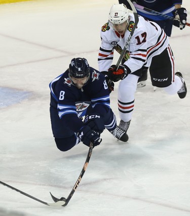 Winnipeg Jets defenceman Jacob Trouba dives to clear a loose puck as he's checked by Chicago Blackhawks centre Dylan Strome in Winnipeg on Thurs., Nov. 29, 2018. Kevin King/Winnipeg Sun/Postmedia Network