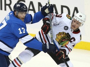 Winnipeg Jets centre Adam Lowry (left) checks Chicago Blackhawks centre Jonathan Toews during Tuesday night's game. (KEVIN KING/Winnipeg Sun)