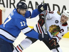 Winnipeg Jets centre Adam Lowry (left) checks Chicago Blackhawks centre Jonathan Toews during Tuesday night's game. (KEVIN KING/Winnipeg Sun)