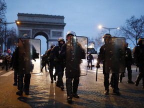 Riot police officers walk on the Champs Elysees avenue during a yellow vest protest, in Paris, Saturday, Dec. 29, 2018. (AP Photo/Thibault Camus)