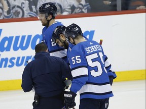 Winnipeg Jets’ Dustin Byfuglien (centre) is assisted off the ice by Blake Wheeler (left) and Mark Scheifele during their game against the Minnesota Wild yesterday. (The Canadian Press)