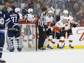 Calgary Flames celebrate Johnny Gaudreau's (13) second goal against the Winnipeg Jets goaltender Connor Hellebuyck during second period in Winnipeg on Thursday.
THE CANADIAN PRESS/John Woods