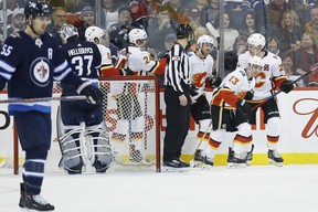 Calgary Flames celebrate Johnny Gaudreau's (13) second goal against the Winnipeg Jets goaltender Connor Hellebuyck during second period in Winnipeg on Thursday.
THE CANADIAN PRESS/John Woods
