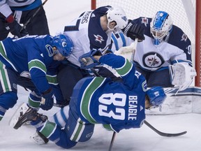 Winnipeg Jets defenceman Tyler Myers (centre) stops Vancouver Canucks centre Jay Beagle from getting a shot on Jets goaltender Laurent Brossoit last night. (The Canadian Press)