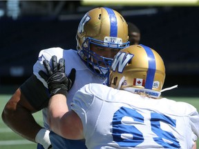 Sukh Chungh (left) blocks Ben Koczwara (65) during Winnipeg Blue Bombers training camp at Investors Group Field on Monday, June 4.