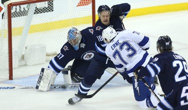 Winnipeg Jets goaltender Connor Hellebuyck stops Tampa Bay Lightning forward Adam Erne as Bryan Little defends in Winnipeg on Sun., Dec. 16, 2018. Kevin King/Winnipeg Sun/Postmedia Network