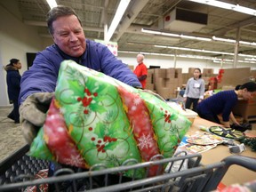 Volunteer Ray Myers helps load a hamper into a shopper cart at the Christmas Cheer board headquarters on St. James Street in Winnipeg on Sunday.