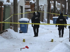 Forensics officers investigate in the backlane of the 400 block between Victor and Toronto Streets, looking north near St. Matthews Avenue, in Winnipeg following a homicide on Christmas Day.