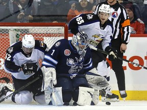 Manitoba Moose goaltender Eric Comrie makes a save with Colorado Eagles forward Scott Kosmachuk in the net behind him in Winnipeg on Sunday. Comrie recorded a 38-save shutout as the Moose beat the Avalanche affiliate 4-0 to improve to 12-16-2-0 on the season.