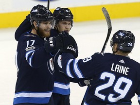 Winnipeg Jets forwards Patrik Laine (right) and Andrew Copp (centre) congratulate centre Adam Lowry on his goal against the Phoenix Coyotes in Winnipeg on Tues., Nov. 14, 2017. Kevin King/Winnipeg Sun/Postmedia Network ORG XMIT: POS1711142118423562