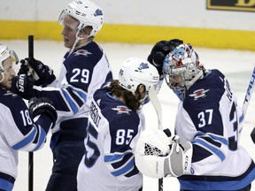 Winnipeg Jets left wing Mathieu Perreault (85) and goaltender Connor Hellebuyck (37) celebrate after an NHL hockey game, Tuesday, Dec. 4, 2018, in New York. The Jets won 3-1. (AP Photo/Julio Cortez) ORG XMIT: NYJC118