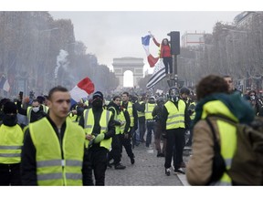 FILE - In this Nov. 24, 2018, file photo, demonstrators march on the famed Champs-Elysees avenue in Paris, France, as they protest the rising of the fuel prices. "Yellow vest" protests have gripped France for four weeks, blocking highways from Provence to Normandy and erupting in rioting in Paris. They've shaken the country to its core and left President Emmanuel Macron struggling to retain control.