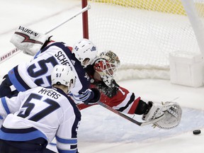 New Jersey Devils goaltender Keith Kinkaid, (right) is unable to stop a shot by Winnipeg Jets centre Mark Scheifele during overtime last night. (AP)