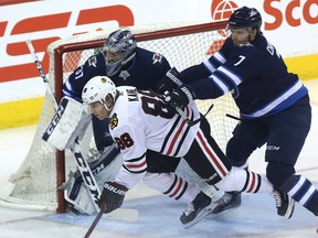 Winnipeg Jets defenceman Ben Chiarot (right) clears  Chicago Blackhawks forward Patrick Kane from the crease of goaltender Connor Hellebuyck in Winnipeg on Thurs., March 15, 2018. Kevin King/Winnipeg Sun/Postmedia Network