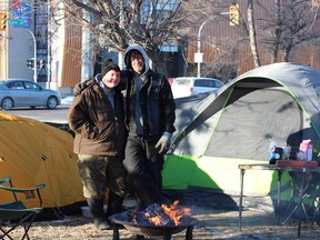 Trevor Sanderson (right) and girlfriend Kim Possible (left) stand outside their tent setup at the corner of Higgins Avenue and Main Street in Winnipeg. The pair are calling for donations for community dinner next Sunday.