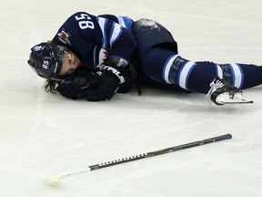 Winnipeg Jets forward Mathieu Perreault lies on the ice after taking a hit from a Philadelphia Flyers player in Winnipeg on Sun., Dec. 9, 2018. Kevin King/Winnipeg Sun/Postmedia Network