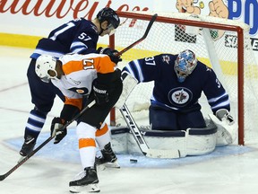 Winnipeg Jets goaltender Connor Hellebuyck fights for a loose puck with defenceman Tyler Myers battling Philadelphia Flyers forward Wayne Simmonds in front of his net in Winnipeg on Sunday.