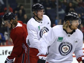 Patrik Laine (centre) sets up in front of the net during Winnipeg Jets practice at Bell MTS Place on Monday.