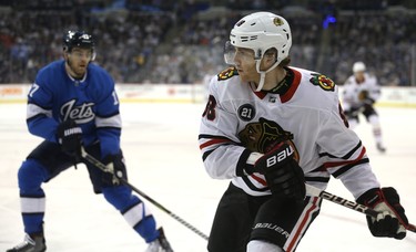 Chicago Blackhawks forward Patrick Kane (right) banks a backhand pass with Winnipeg Jets centre Adam Lowry defending in Winnipeg on Tues., Dec. 11, 2018. Kevin King/Winnipeg Sun/Postmedia Network