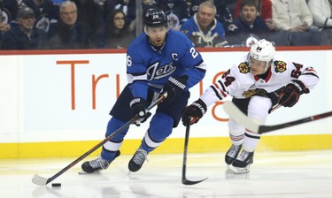 Winnipeg Jets forward Blake Wheeler (left) carries the puck under pressure from Chicago Blackhawks centre David Kampf in Winnipeg on Tues., Dec. 11, 2018. Kevin King/Winnipeg Sun/Postmedia Network