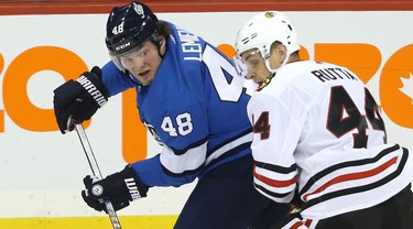 Winnipeg Jets forward Brendan Lemieux (left) watches his backhand pass as he is checked by Chicago Blackhawks defenceman Jan Rutta in Winnipeg on Tues., Dec. 11, 2018. Kevin King/Winnipeg Sun/Postmedia Network