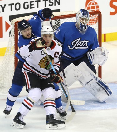 Chicago Blackhawks centre Jonathan Toews (centre) and Winnipeg Jets centre Bryan Little battle for position in front of goaltender Laurent Brossoit in Winnipeg on Tues., Dec. 11, 2018. Kevin King/Winnipeg Sun/Postmedia Network