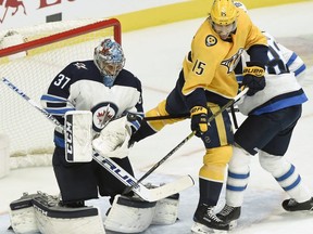 Winnipeg Jets goaltender Connor Hellebuyck (37) stops a shot as Nashville Predators right wing Craig Smith (15) looks for a rebound during the second period of an NHL hockey game Thursday, Jan. 17, 2019, in Nashville, Tenn. (AP Photo/Mark Zaleski)