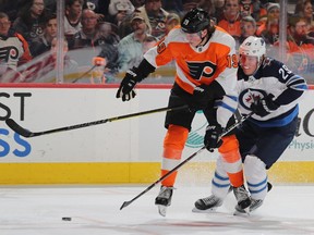 PHILADELPHIA, PENNSYLVANIA - JANUARY 28:   Nolan Patrick #19 of the Philadelphia Flyers and Patrik Laine #29 of the Winnipeg Jets fight for the puck in the second period at Wells Fargo Center on January 28, 2019 in Philadelphia, Pennsylvania. (Photo by Elsa/Getty Images)