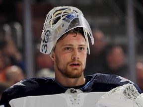 PHILADELPHIA, PENNSYLVANIA - JANUARY 28:   Laurent Brossoit #30 of the Winnipeg Jets looks on during a stop in play in the second period against the Philadelphia Flyers at Wells Fargo Center on January 28, 2019 in Philadelphia, Pennsylvania. (Photo by Elsa/Getty Images)