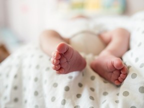 Close up, legs of unrecognizable newborn baby boy lying in bed, sleeping.