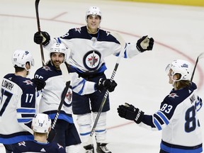 Winnipeg Jets left wing Brandon Tanev, top, celebrates with teammates after scoring a goal against the Nashville Predators during the third period of an NHL hockey game Thursday, Jan. 17, 2019, in Nashville, Tenn. The Jets won 5-1.