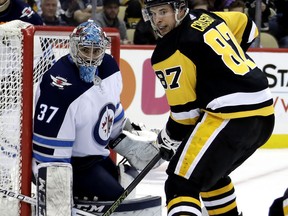 Pittsburgh Penguins' Sidney Crosby (87) looks for the puck in front of Winnipeg Jets goaltender Connor Hellebuyck (37) during the second period of an NHL hockey game in Pittsburgh, Friday, Jan. 4, 2019.