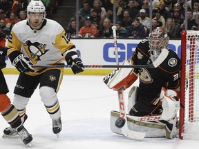 Anaheim Ducks goaltender John Gibson, right, blocks a shot by Pittsburgh Penguins center Dominik Simon during the first period of an NHL hockey game in Anaheim, Calif., Friday, Jan. 11, 2019.