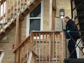 A forensics officer prepares to step off a second-storey ledge at a three-storey apartment complex on Ellice Avenue at Maryland Street in Winnipeg that was the scene of a fire in the early morning hours on Sunday. About 30 people were safely evacuated, including two people who were clinging to a second-storey ledge.